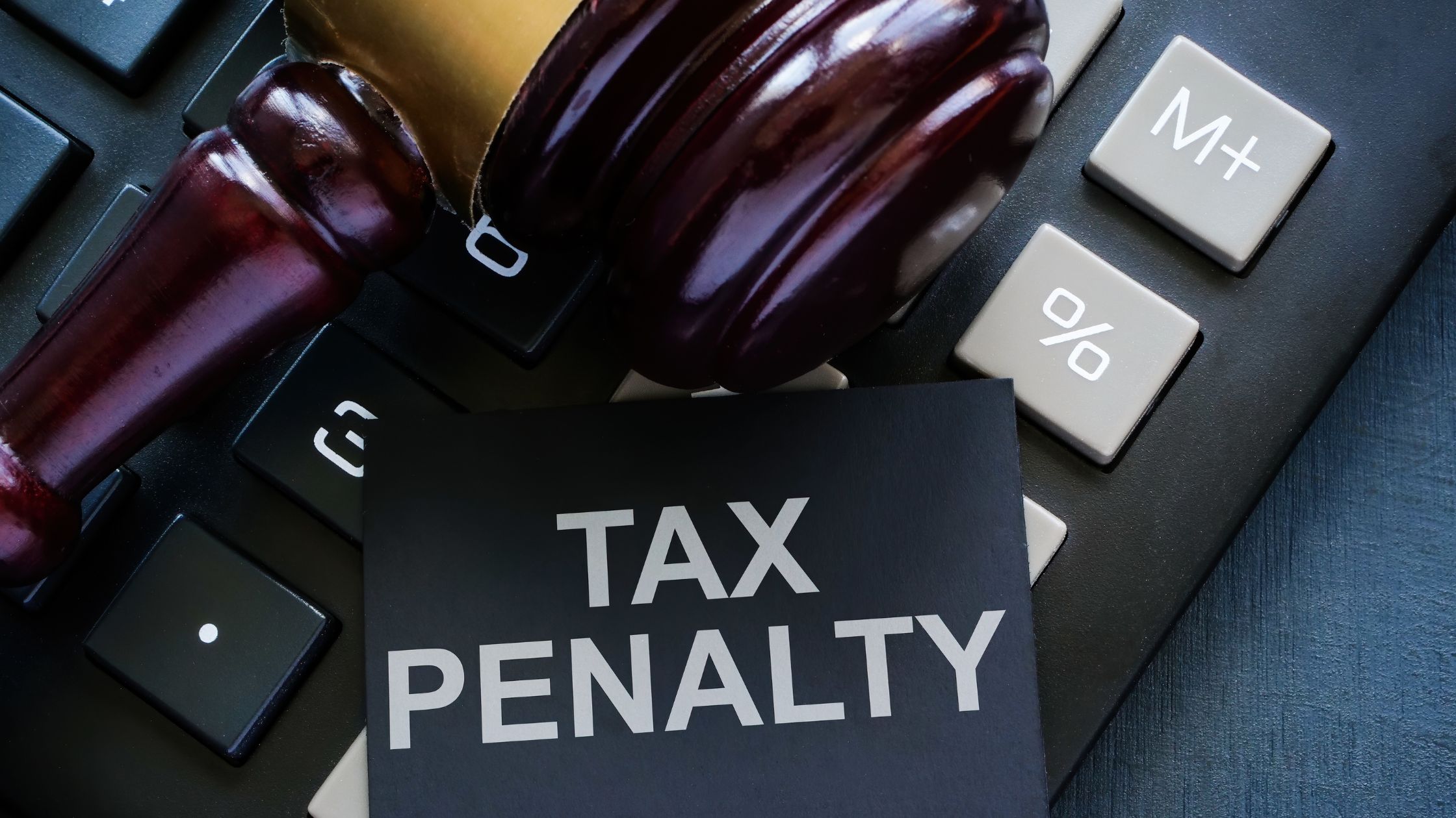 A gavel rests on a computer keyboard with a note that says tax penalty.